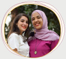Zwei junge Freundinnen mit Migrationshintergrund, lächelnd